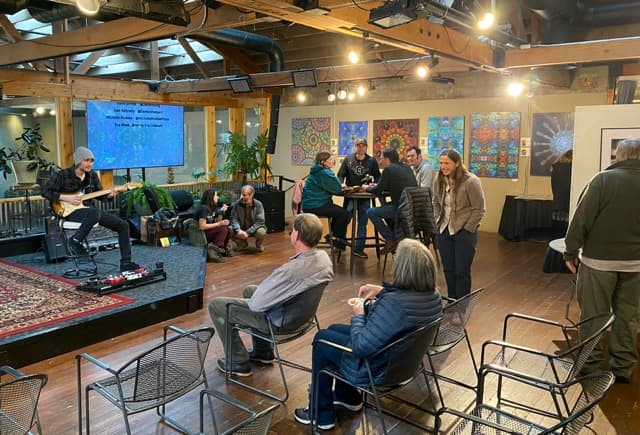Guitar player performing during gallery night with art on the walls at The Hivve
