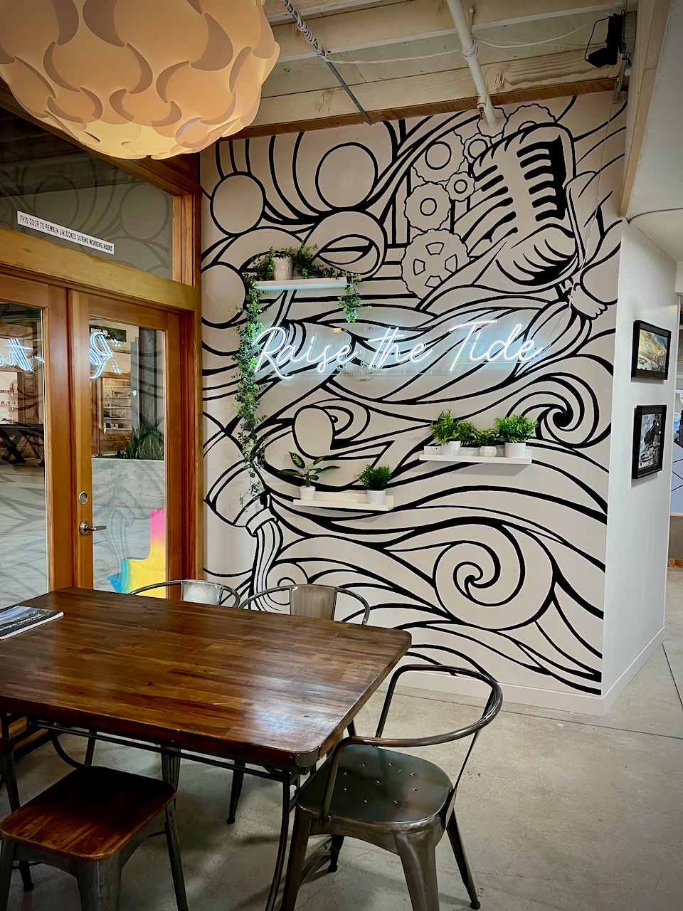 The Hivve coworking space interior with 'Raise the Tide' neon sign